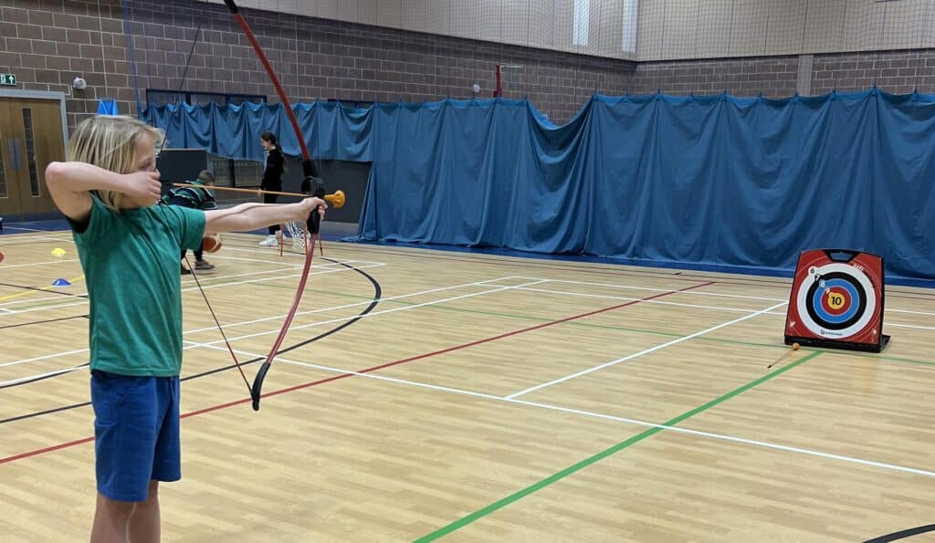 Young person aiming bow in indoor archery in a sports hall in West Wales